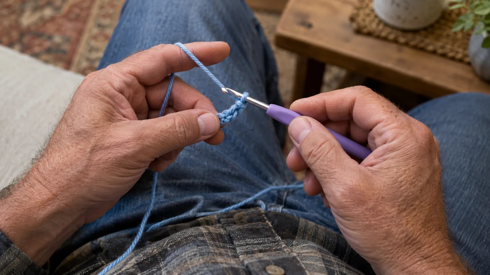 A person's hands starting a crochet loop with a hook and yarn on a lap